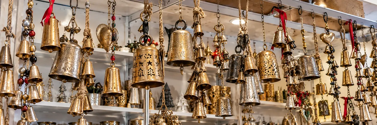 Shelves of handmade metal bells: etched brass bells, silver-finish bells and harmony bell strings with red ribbons
