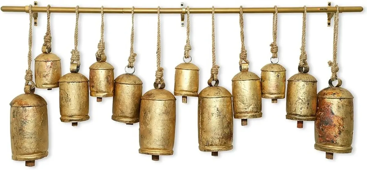 Row of handmade golden cow bells hanging from a brass rail